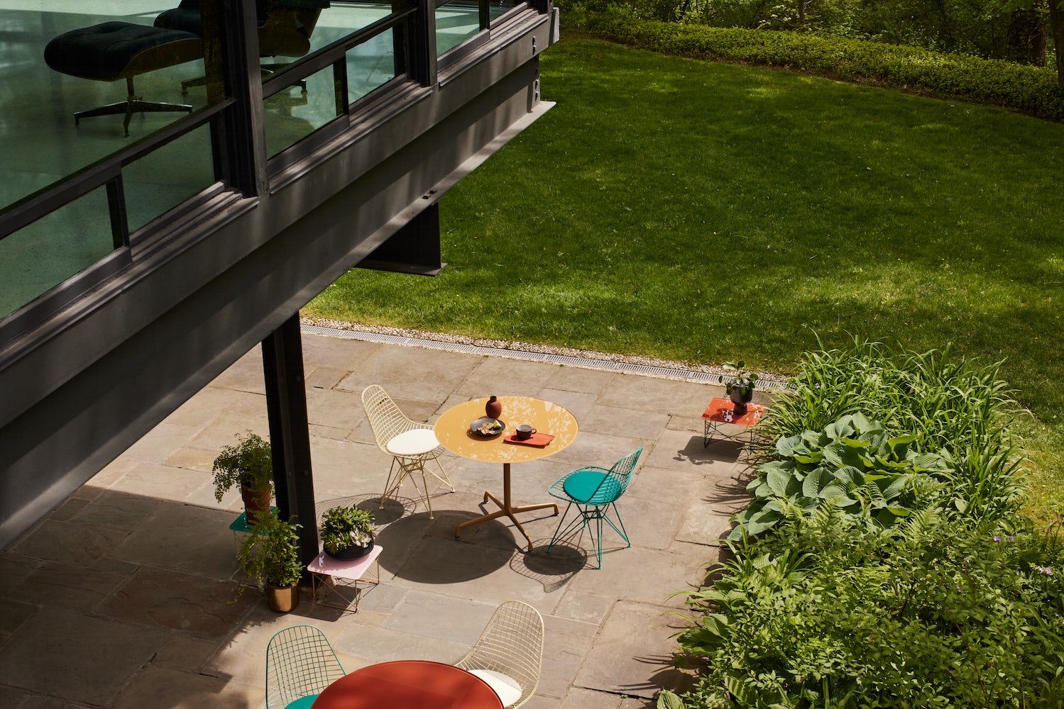 A sunny living room full of vibrant furnishings: a striped sofa, pastel coffee tables, and green side chair.