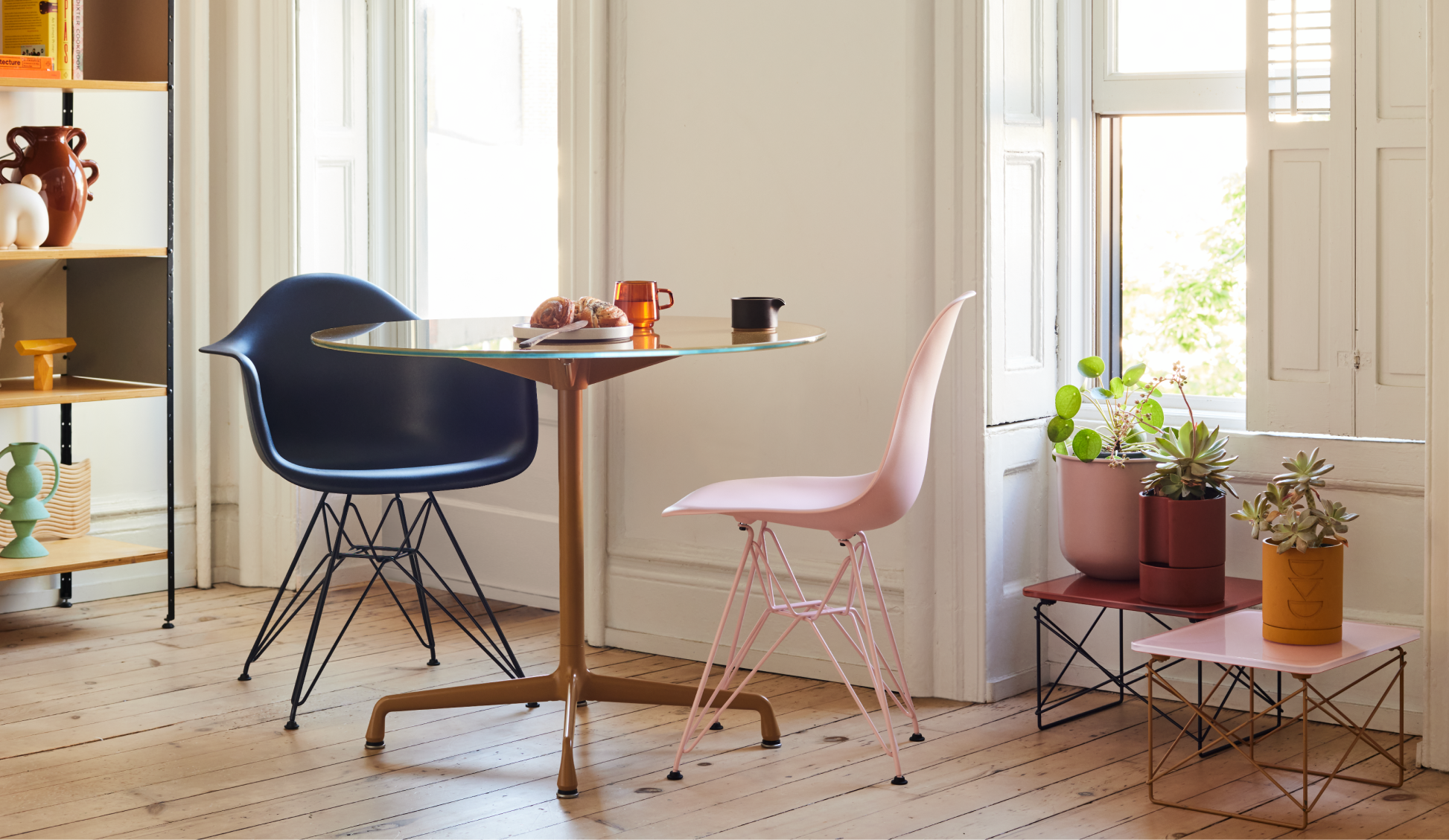 A sunny living room full of vibrant furnishings: a striped sofa, pastel coffee tables, and green side chair.