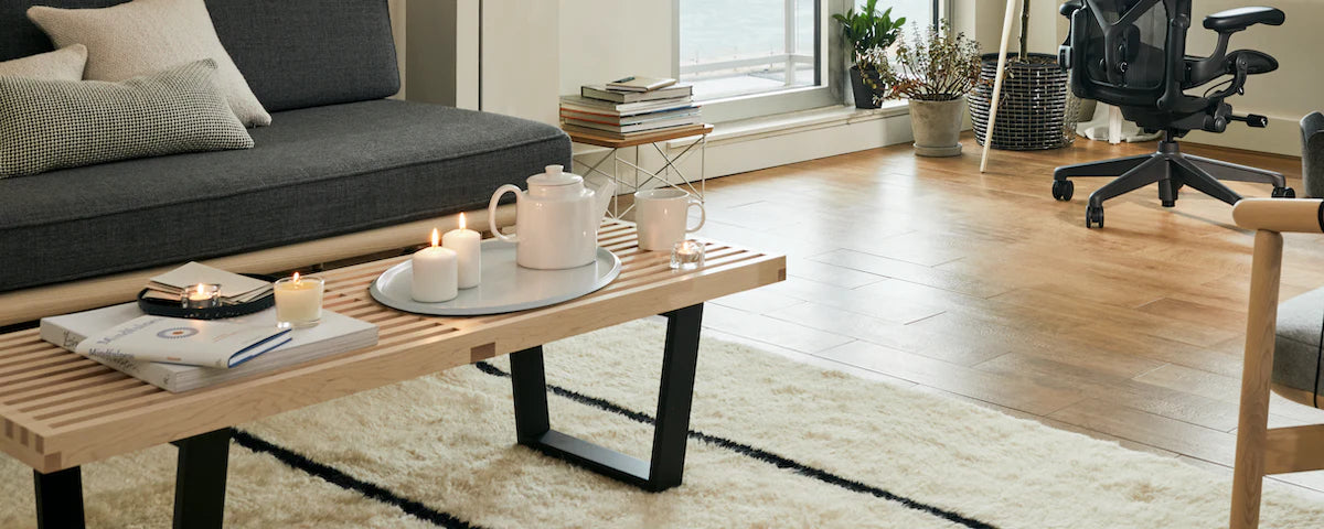 An AbakEnvironments Desk with a walnut top and polished legs, with a graphite Aeron Chair in a light home office setting and Folk Ladder Shelving.