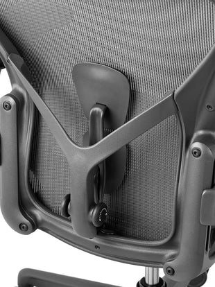 Rear view of a graphite Aeron office chair, showing back support and adjustable arms.