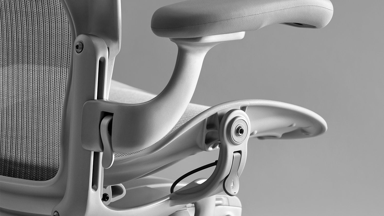 Close-up of the Pelicle mesh back and the arm adjustment thumb latch on a mineral Aeron office chair
